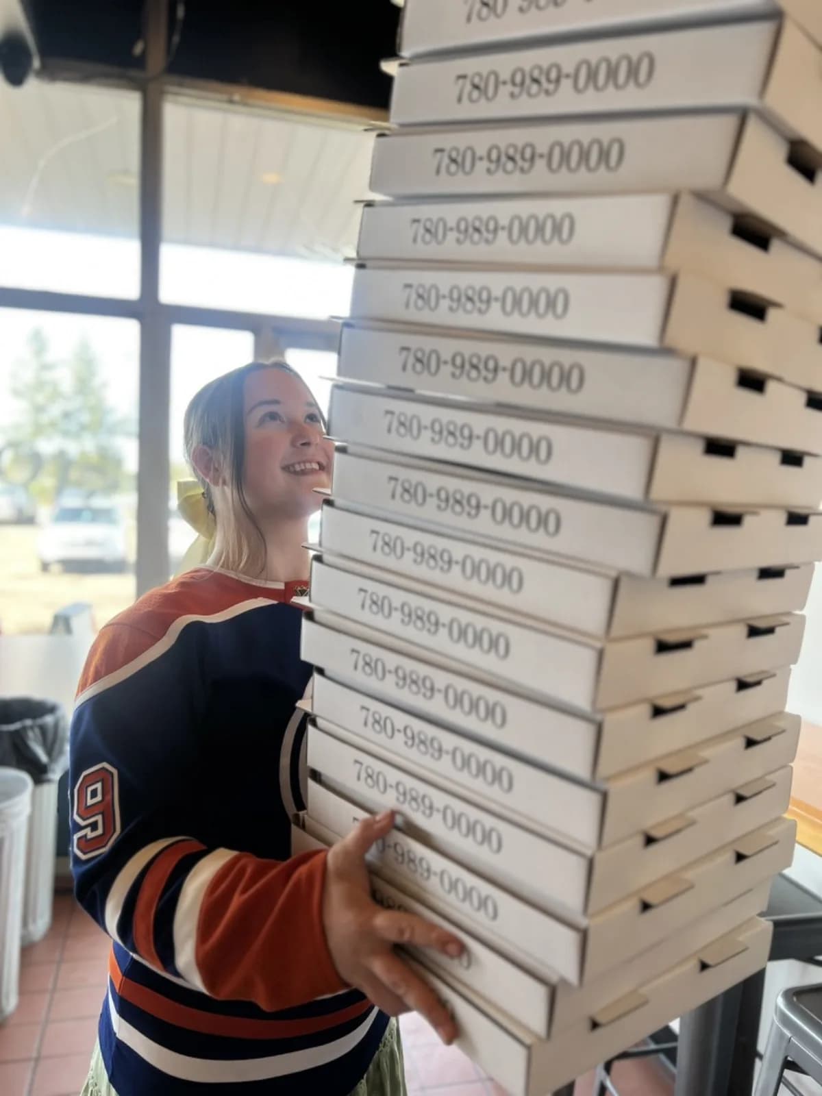 A Stone & Wheel team member carrying a tall stack of pizza boxes for a large order