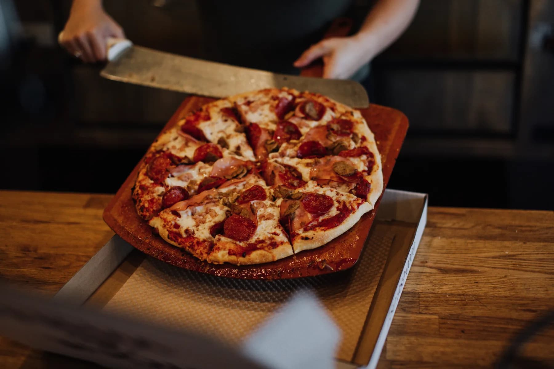 A fresh pepperoni pizza lifted on a serving board